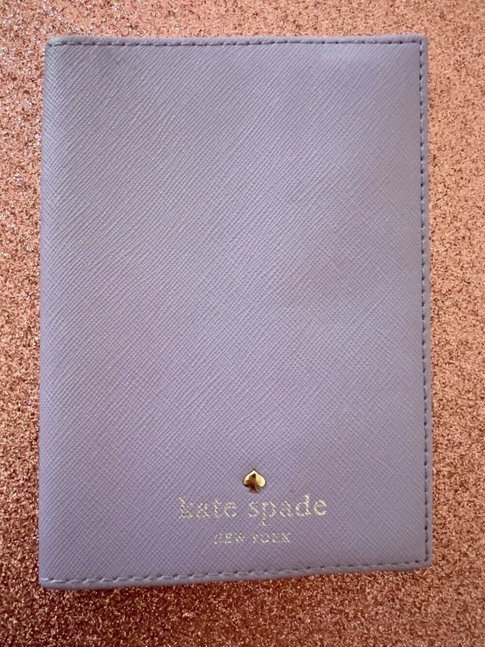 purple Kate Spade passport holder with a small gold spade emblem